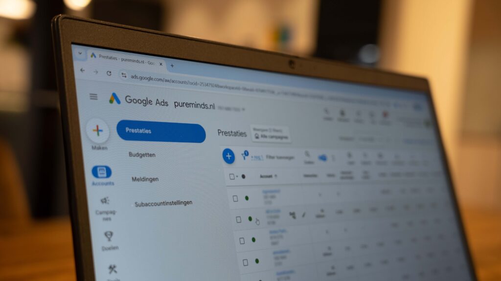 Dienst_Google_Ads_blurred Laptop met een geopend Google Ads-dashboard waarop campagneprestaties en accountinstellingen zichtbaar zijn, gefotografeerd met onscherpe achtergrond.