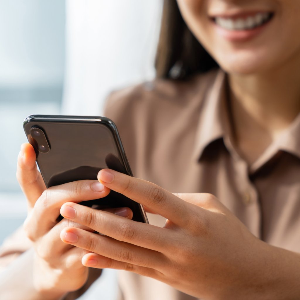 1 Mevrouw die een zwarte telefoon in de hand heeft en kijkt naar het beeldscherm.